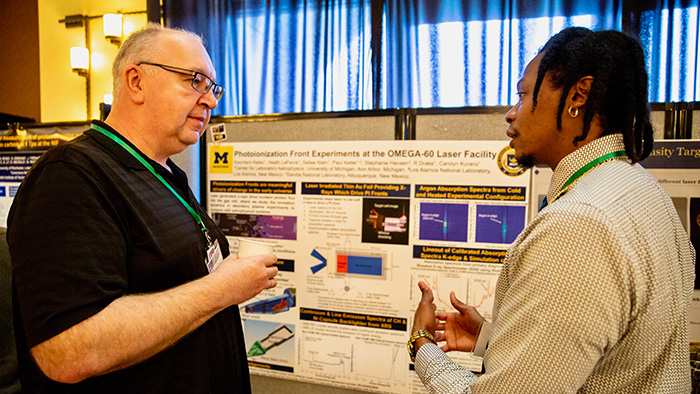 Kwyntero Kelso, a graduate student at the University of Michigan, right, discusses his poster with Igor Golovkin from Prism Computational Sciences, Inc.