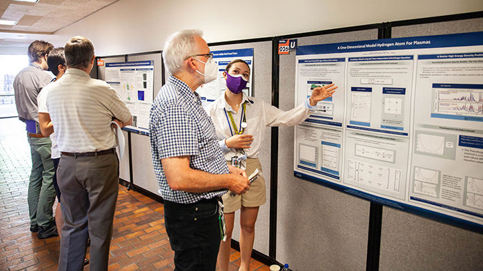 NIF&PS summer intern Isabella Martinez explains her poster symposium entry to physicist John Moody