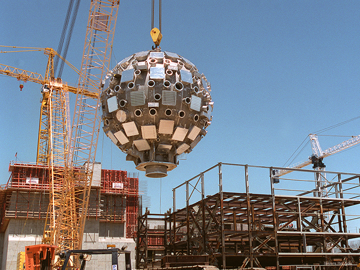 Photo of the 900-ton crane lifting the assembled Target Chamber toward NIF.