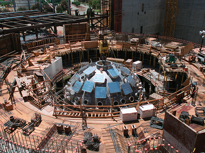 A crane places the assembled Target Chamber in the partially completed Target Bay in 1999