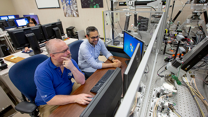 Photo of Lyle Beaulac and Jorge Castro Morales running system simulations inside the Integrated Computer Control System (ICCS) test-bed testing facility