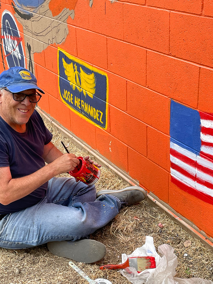 Larry Lagin, former NIF deputy project manager, works on the mural near the image of José Hernández