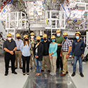 A group that included the 100,000th visitor to NIF pose in front of the Target Chamber