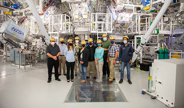 A group that included the 100,000th visitor to NIF poses in front of the Target Chamber