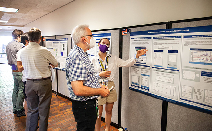 Isabella Martinez, a NIF&PS summer intern, explains her poster symposium entry to physicist John Moody